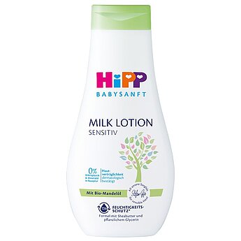 A zöld kupakkal ellátott fehér üveg "HiPP BABYSANFT MILK LOTION SENSITIV" felirattal, fa grafikával és német nyelvű szöveggel.