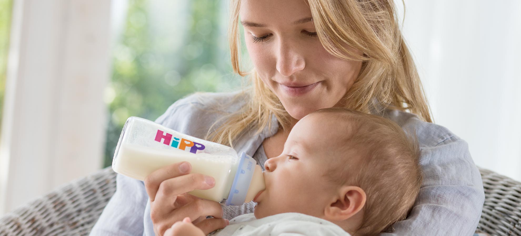 A woman feeds a baby with a Hipp bottle.