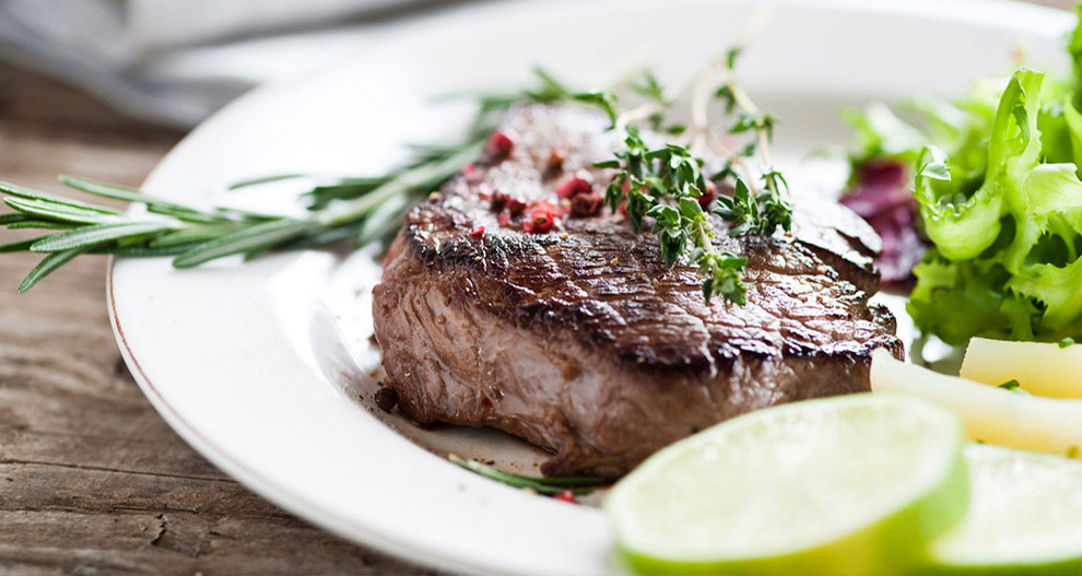 Rozmaringgal és kakukkfűvel díszített steak, zöldsalátával és lime szeletekkel tálalva.