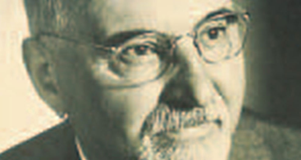 Közelkép egy férfi arcáról, melyen a szeme, az orra és a szája látható, szakállas, bajuszos, szemüveges férfi.